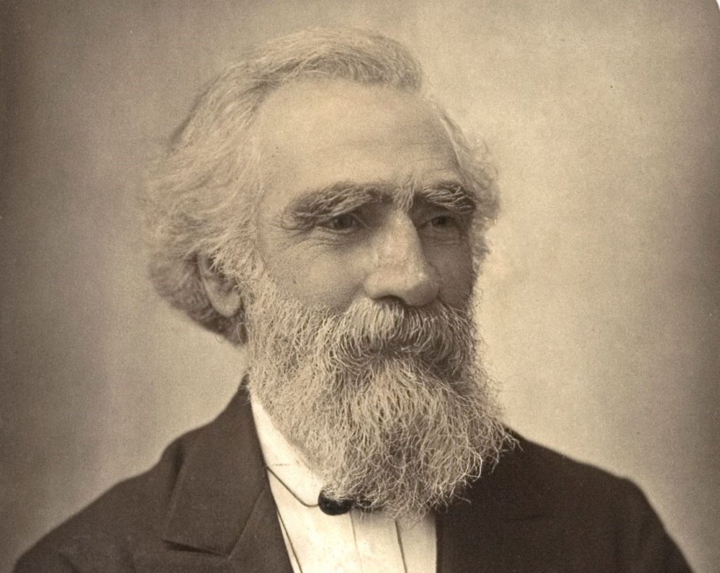 Black and white, sepai toned photo of beared man, known to be John Passmore Edwards